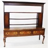 A George III oak and mahogany cross banded Welsh dresser, the open plate rack with a cavetto cornice