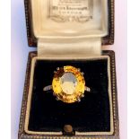 An 'imperial' topaz and diamond ring, the central oval mixed cut orange-yellow topaz measuring 13.