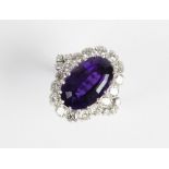 An amethyst and diamond cocktail ring, the central oval step cut amethyst (measuring 15.5mm x 10mm x