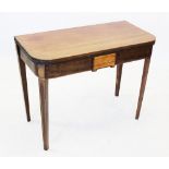 An early 19th century mahogany folding tea table, the 'D' shaped top above a frieze centred with a