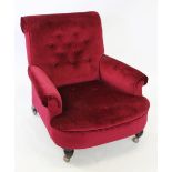 A Victorian claret upholstered arm chair, the deep set button back above padded scrolled arms and