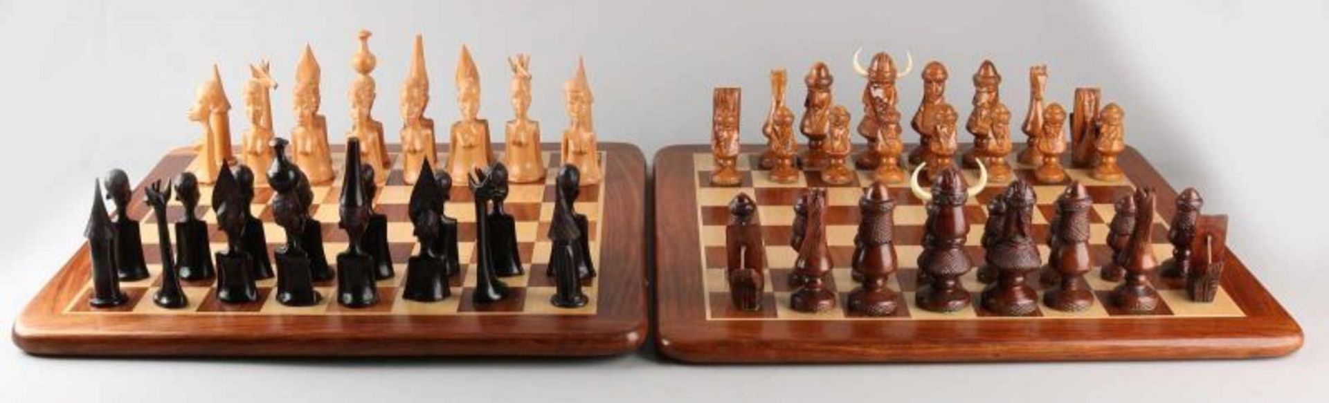 Two carved chess sets. One time set Normans + wooden chessboard. One time set Africa, Madagascar +
