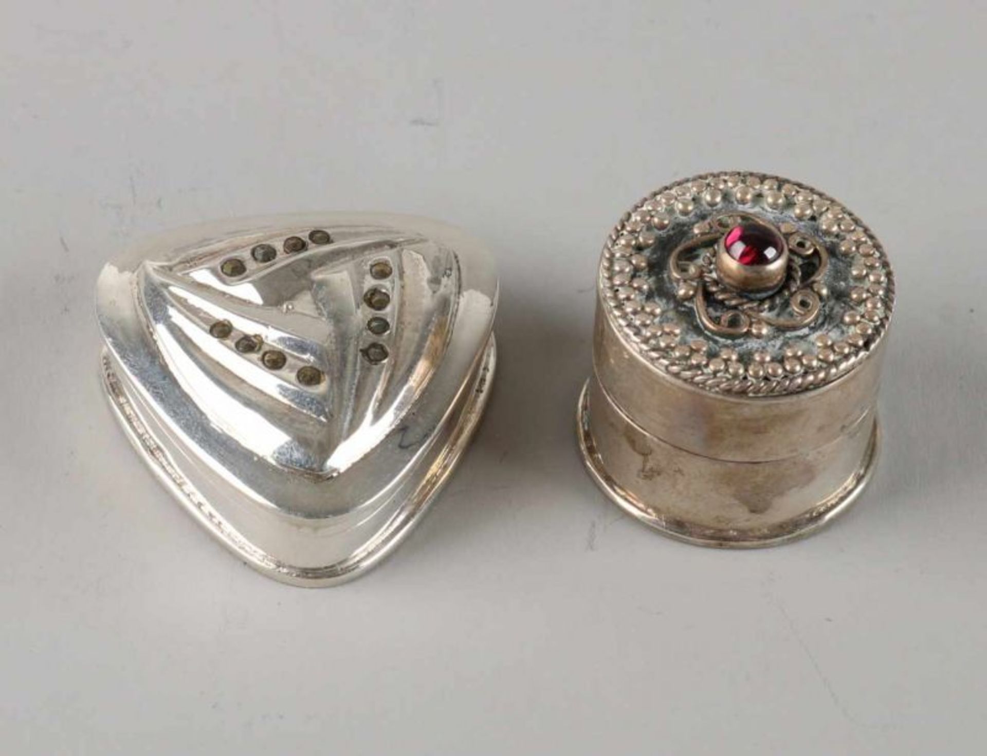 Two silver pillboxes, 925/000, a round box, decorated with filigree and a red stone, ø2,5x2,5cm