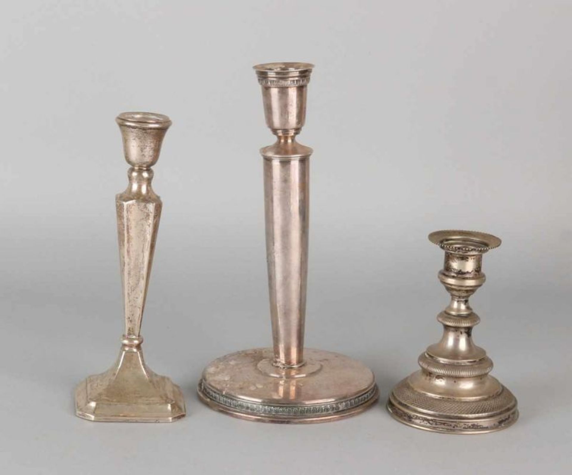 Lot with three silver candlesticks, a big table candlestick on circular base with knerrenrand, 830/