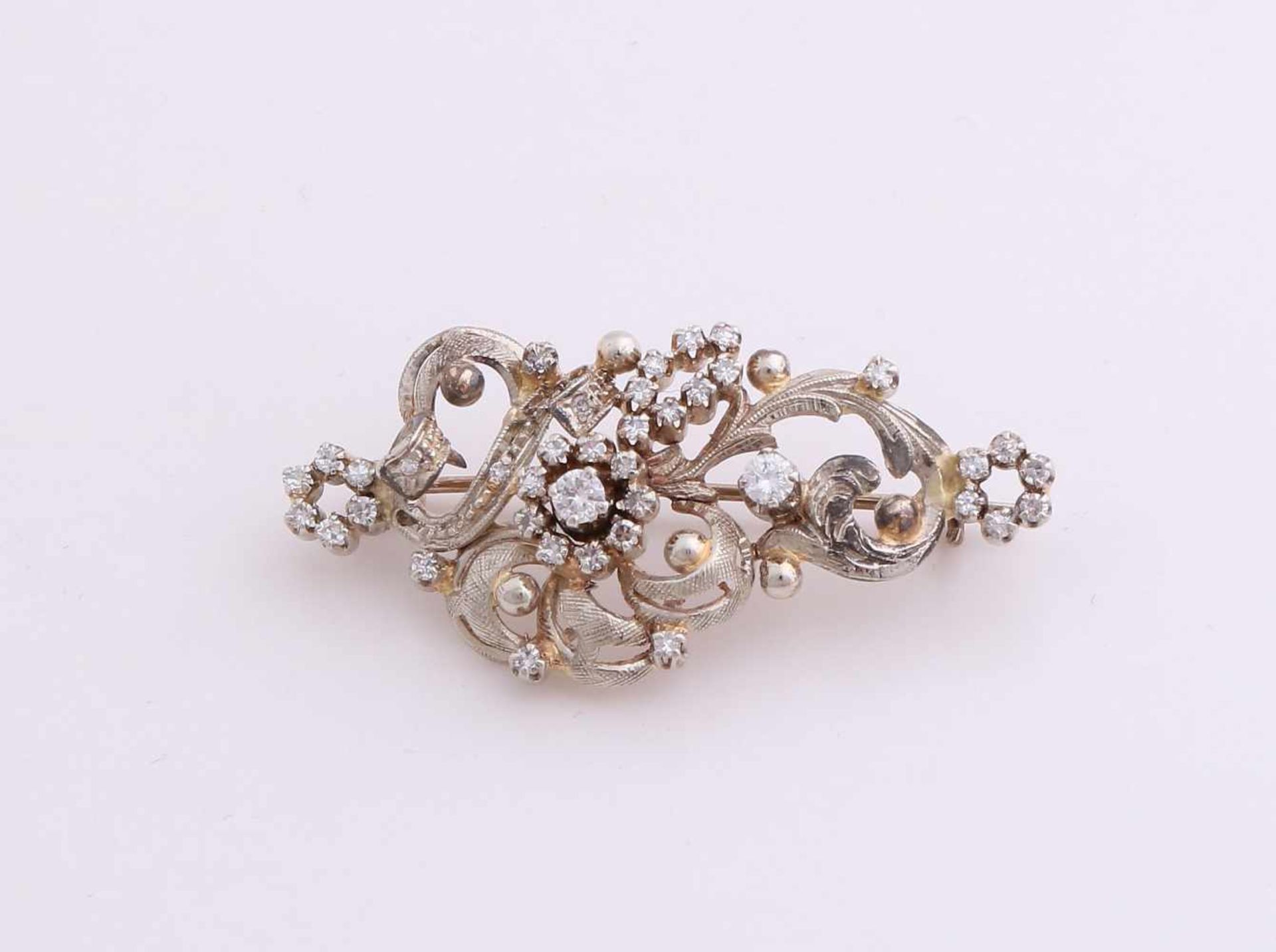 White gold brooch, 585/000 with diamond. Ornate brooch with curls and flowers set with brilliant cut