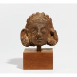 TERRACOTTA HEAD WITH HAIR JEWELS AND EAR FLOWER DECORATION. Origin: India. Date: Prob. Gupta