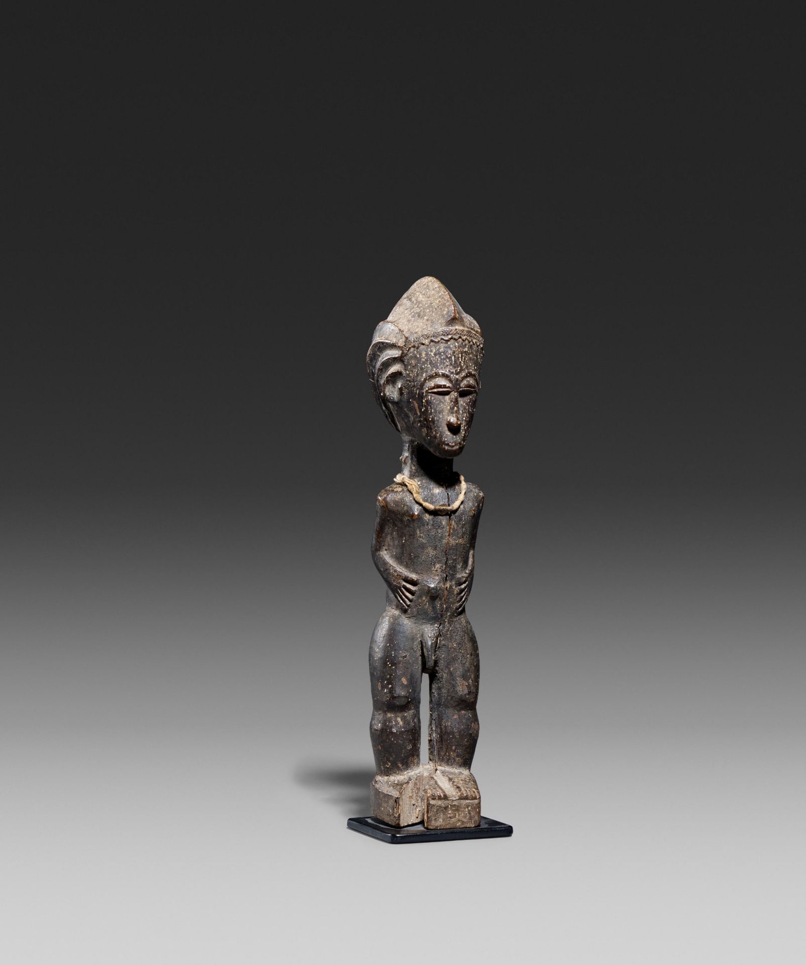 BAULE, Ivory Coast. Male figure. Wood, string necklace with small piece of metal, encrusted