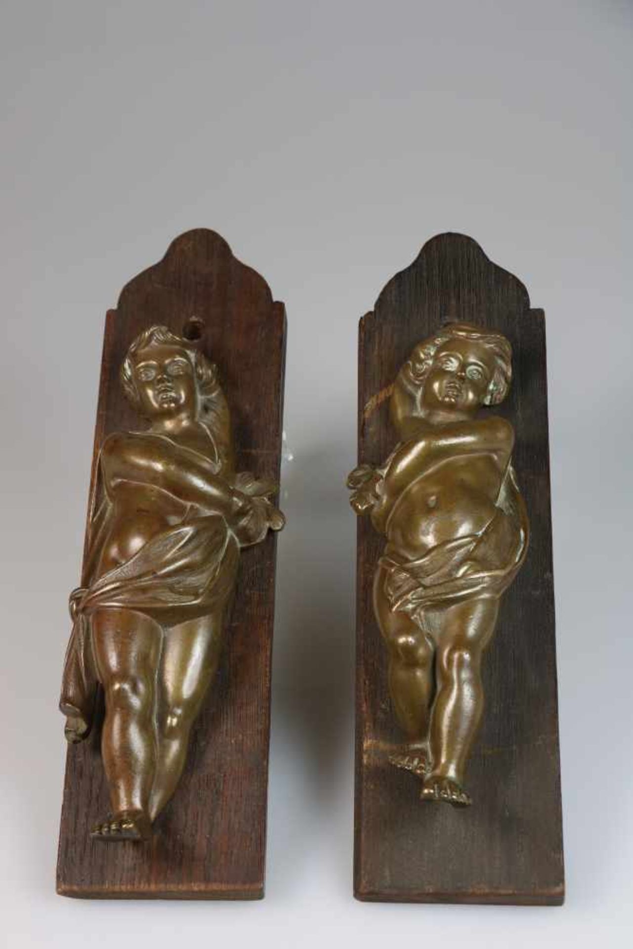 Twee bronzen putti, gemonteerd op paneeltjes, 1e helft 20e eeuw.Afm. 37 x 9,5 x 7 cm. Geschatte