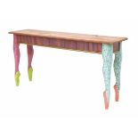 WinslettiA wooden sidetable, the feet shaped as lady's legs, colourfully decorated, signed