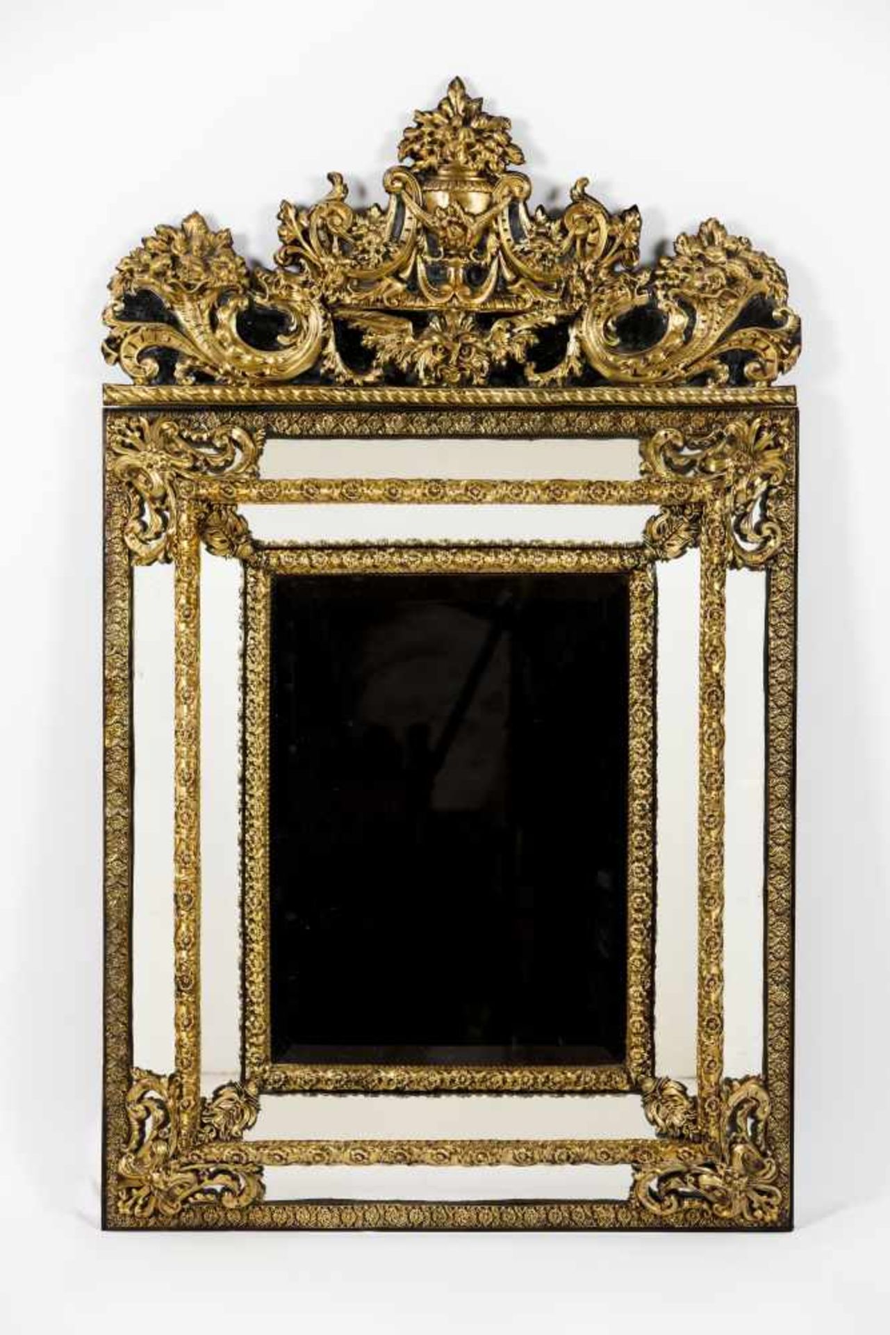 A large mirrorDeep slanted wooden frameRaised and gilt metal floral and foliage decoration<