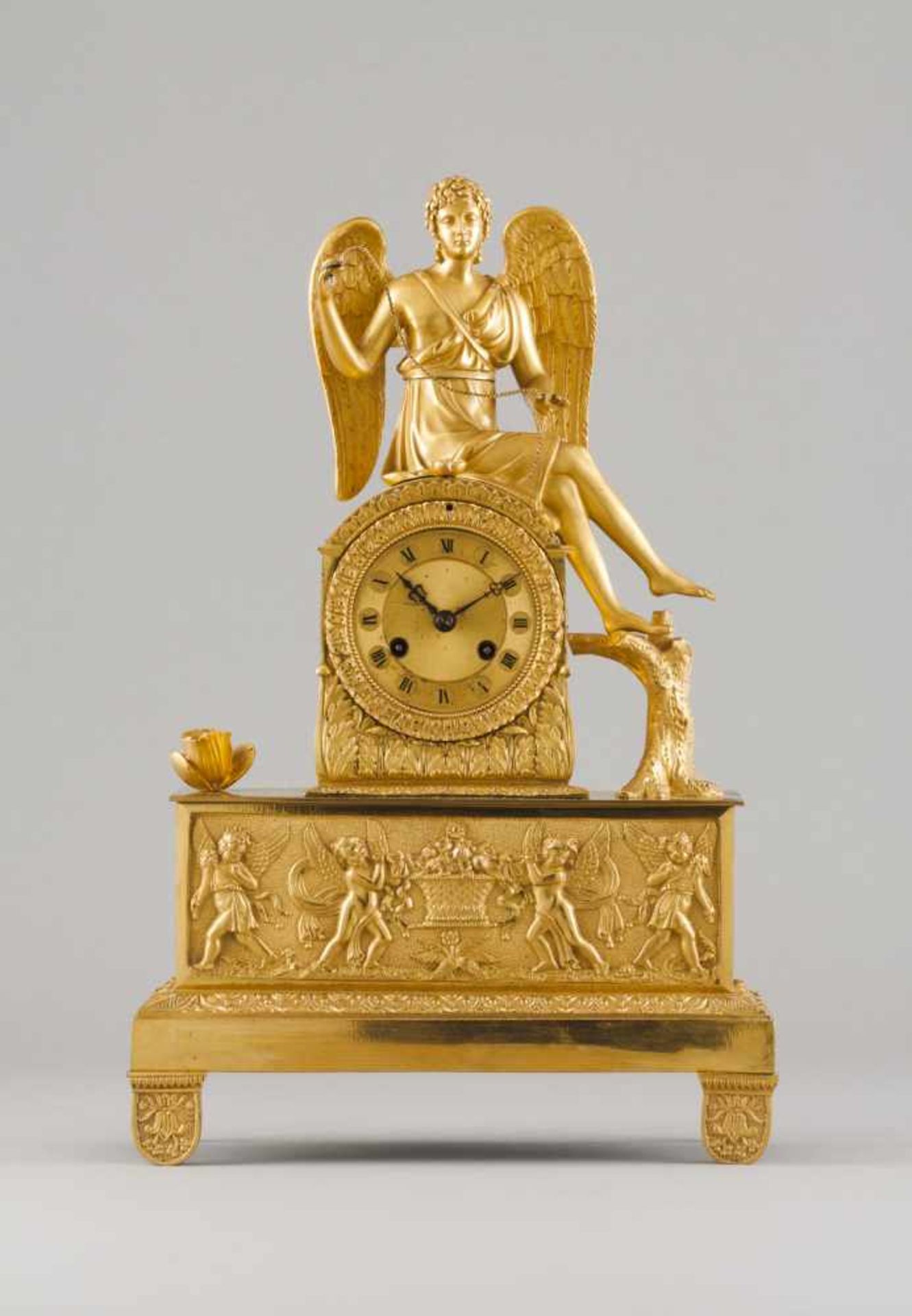 A Napoleon III table clockGilt bronzeRaised foliage and putti decorationTopped by winge