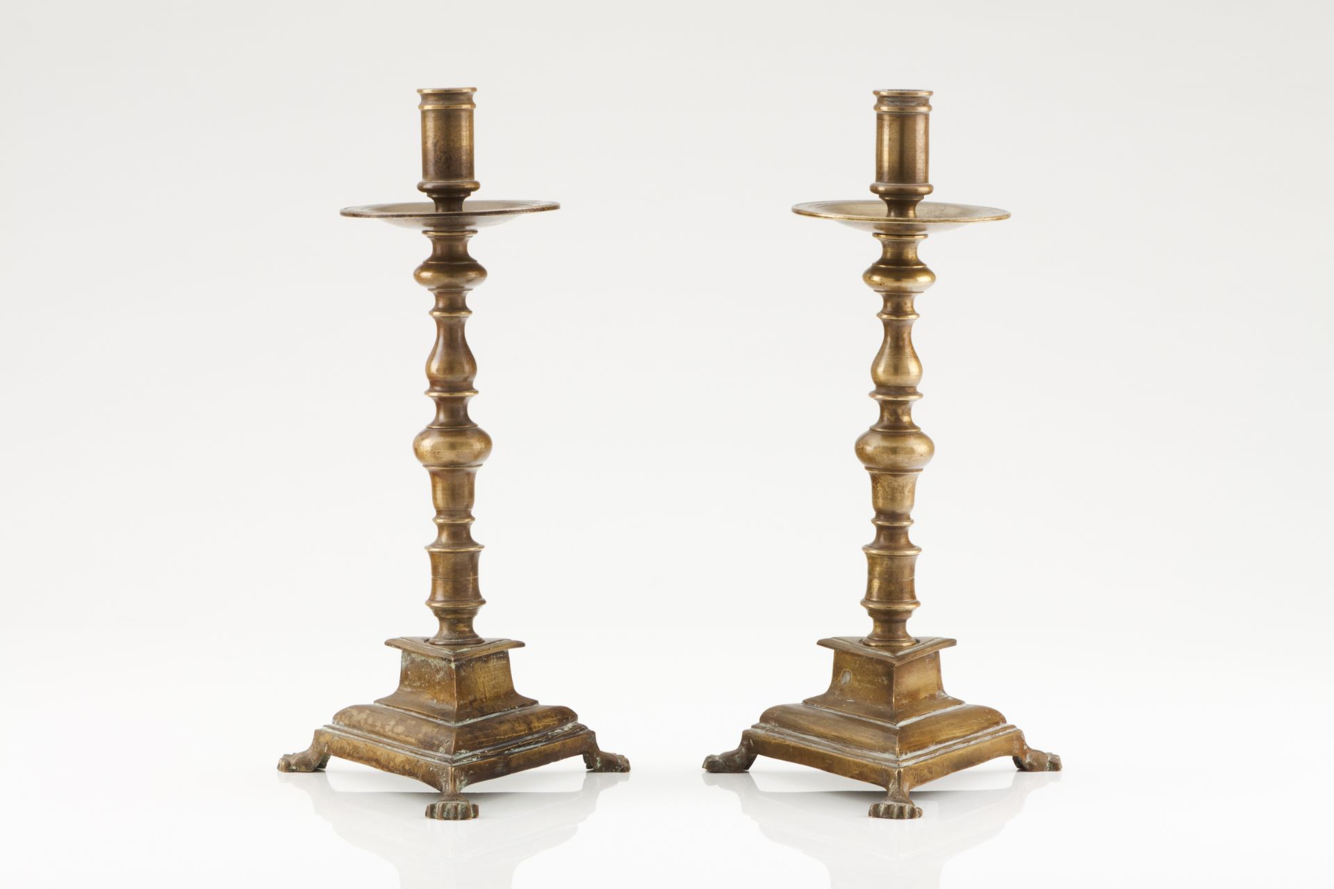 A pair of Iberian candlesticksYellow metalTriangular stand and turned shaftZoomorphic feet17th