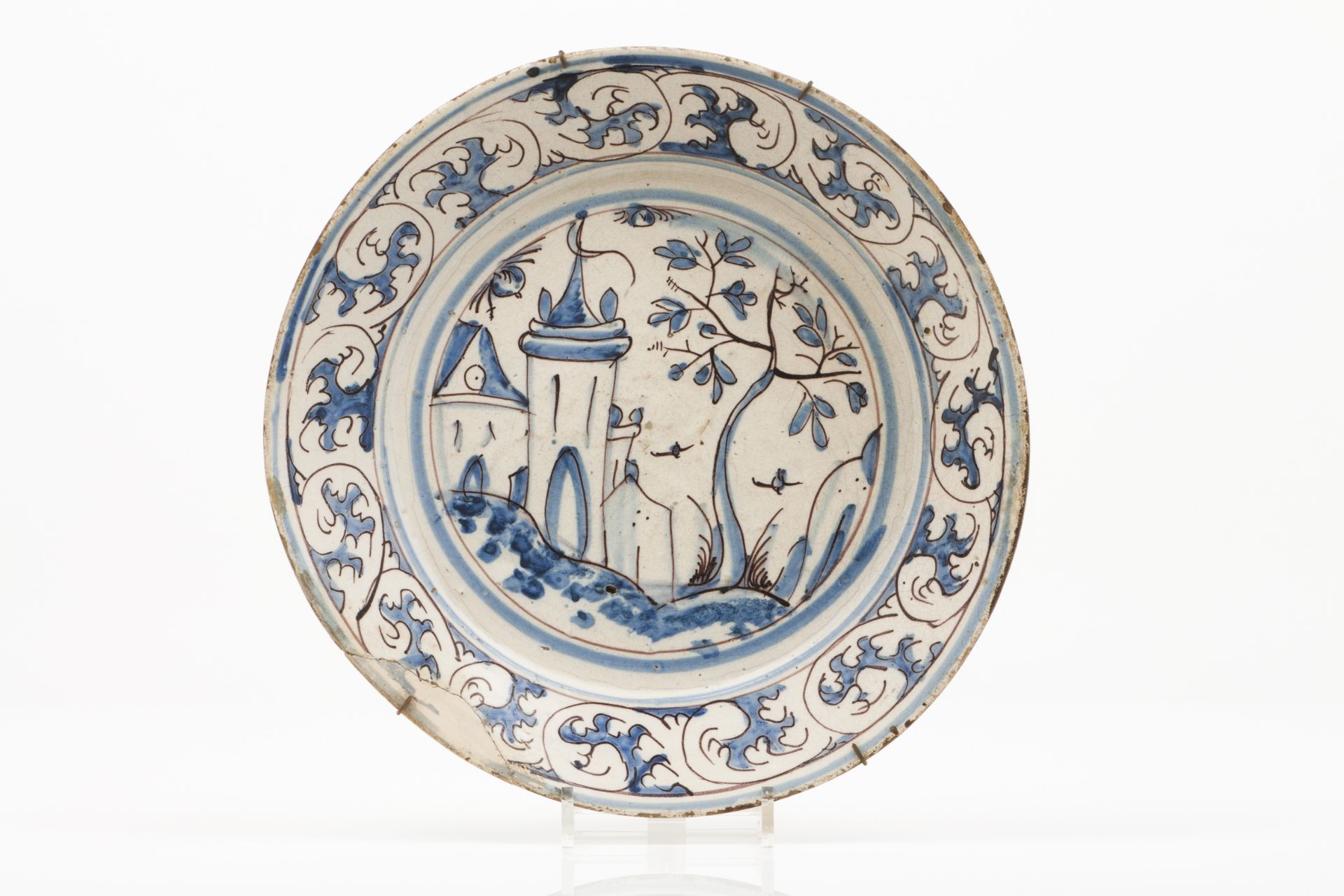 A plateFaienceCobalt blue and manganese decoration with central landscape with buildings and baroque