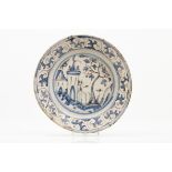 A plateFaienceCobalt blue and manganese decoration with central landscape with buildings and baroque