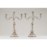 A pair of three branch candelabraPortuguese silver, 19th centuryA page boy holding a cornucopia