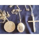 Three sterling silver chains and pendants including a crucifix, locket and a silver half dollar.