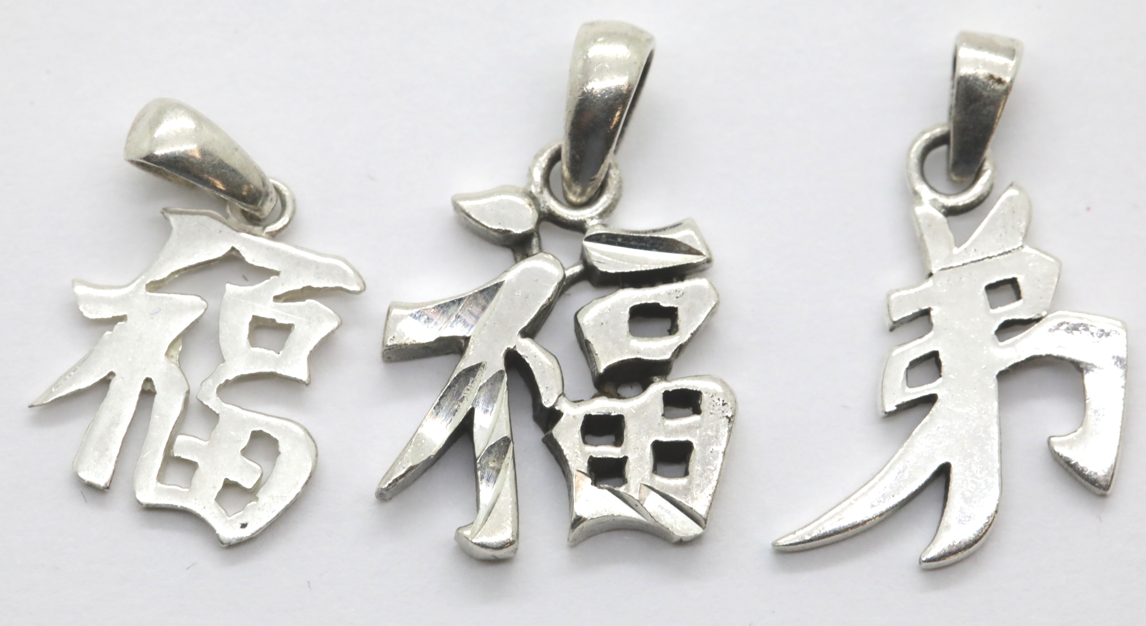 Three silver Chinese symbol charms. P&P Group 1 (£14+VAT for the first lot and £1+VAT for subsequent