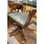 Reproduction mahogany and green leather upholstered swivel base captains chair raised on castors.