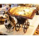 Reproduction longcase clock face with two ceramic dogs and miniature Victorian pram. This lot is not