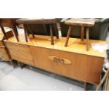 Mid Century teak sideboard of asymmetric design having a flight of three drawers and two cupboard