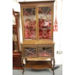 An Edwardian mahogany display cabinet, the glazed base with under shelf supports a red velvet