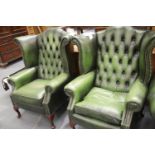 A pair 20thC Chesterfield style wingback armchairs in green leather, H: 108 cm. This lot is not