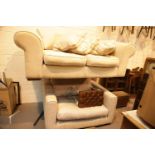 Cream upholstered two seater sofa and a grey oversized armchair. This lot is not available for in-