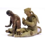 Clay figurines depicting a tribal man and an Oriental man dressed in traditional dress, both A/F.