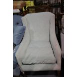 An early 20th century upholstered bedroom chair with overstuffed cushion, raised on tapering