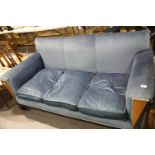 An Art Deco walnut framed three seater settee, upholstered in blue, in the style of Waring and