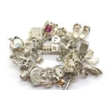 Heavy silver charm bracelet with more than twenty charms, 114g. P&P Group 1 (£14+VAT for the first