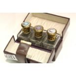 Three enamel topped perfume bottles in fitted leather case. P&P Group 1 (£14+VAT for the first lot