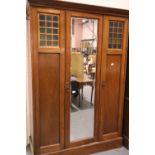 Arts and Crafts mahogany combination wardrobe, three doors with full length bevelled mirror, the