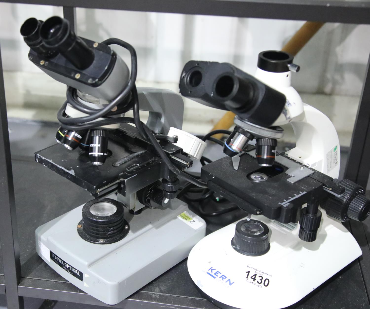 Two binocular microscopes, by Kern and Kyowa Optical, both lacking one eyepiece lens, each with four