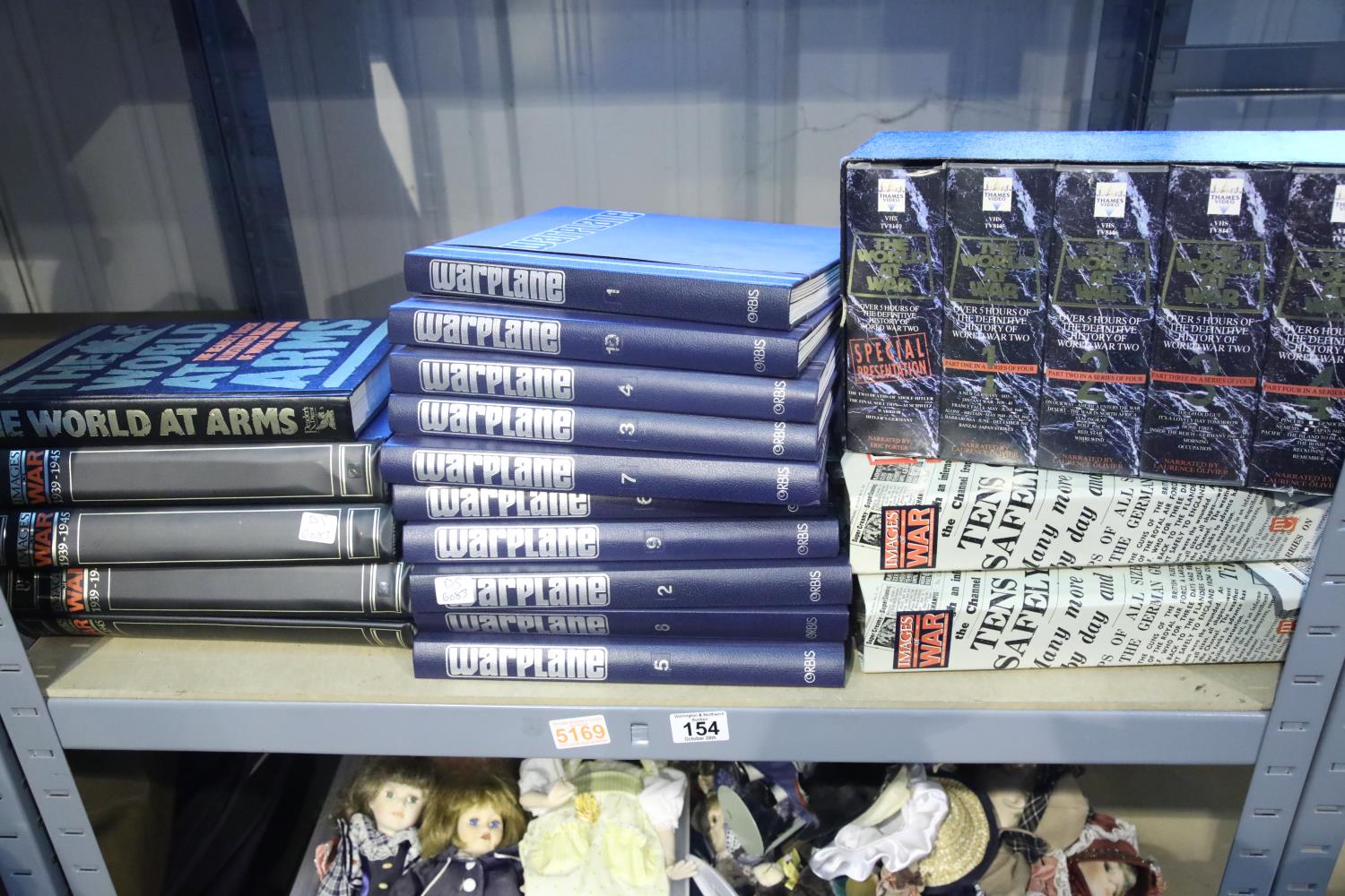 Shelf of binders of wartime images and war planes in binder folders and video cassettes of the world