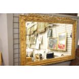 Carved gilt framed bevelled edged mirror, 108 x 80 cm. Not available for in-house P&P
