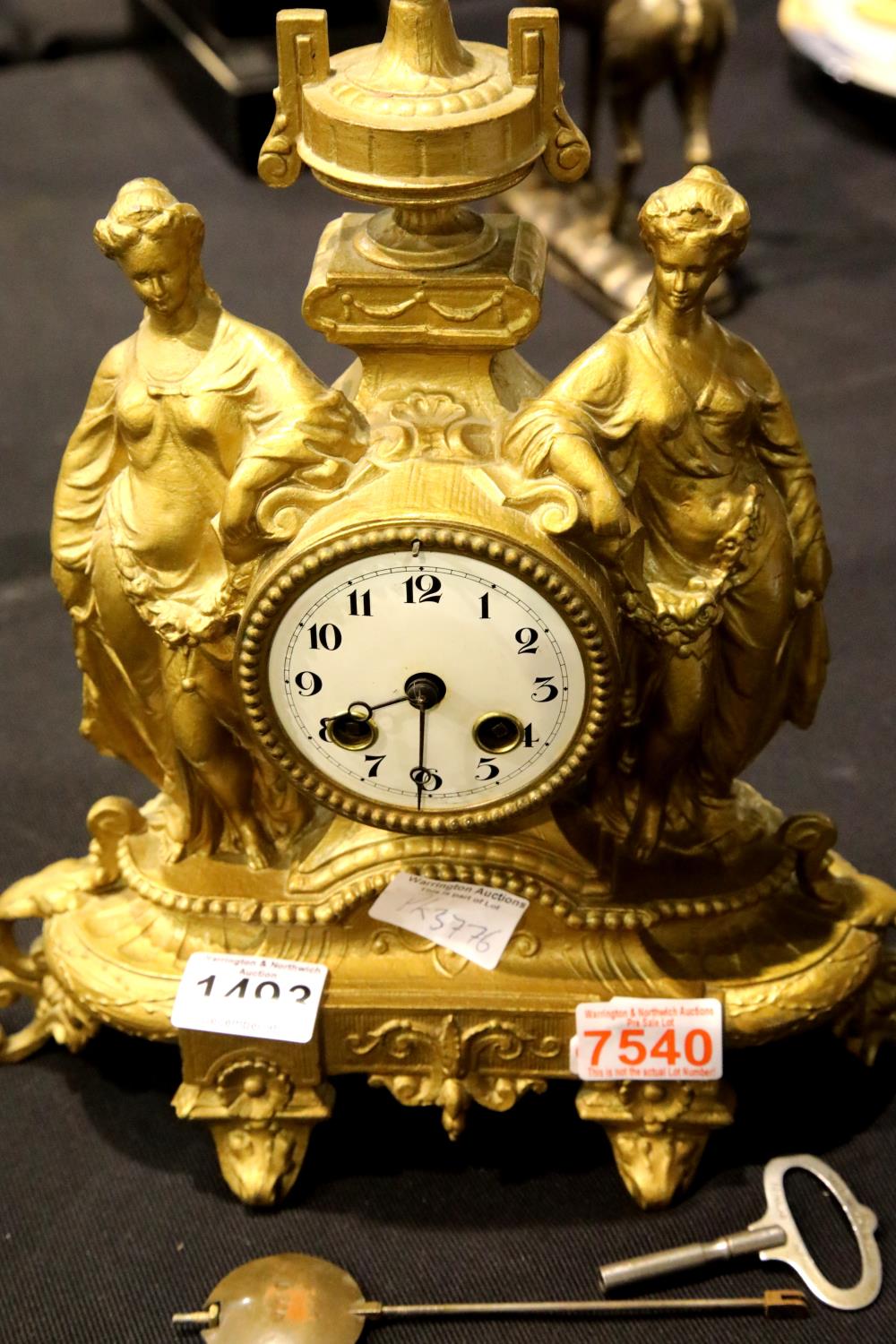 Antique gilt cast metal chiming clock depicting two Grecian ladies in full dress either side of