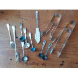 A collection of silver flatware comprising sugar tongs, butter knife, pickle forks,mustard spoons et