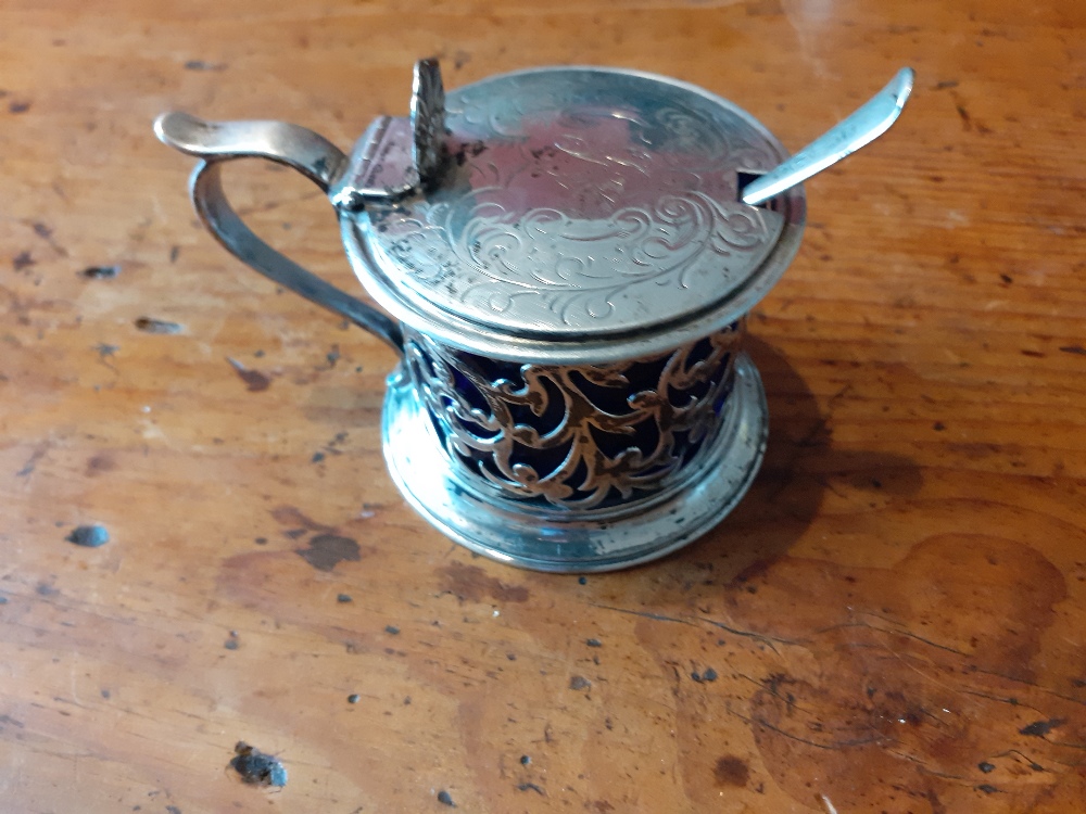 A silver mustard pot with pierced decoration to the body and chased lid.