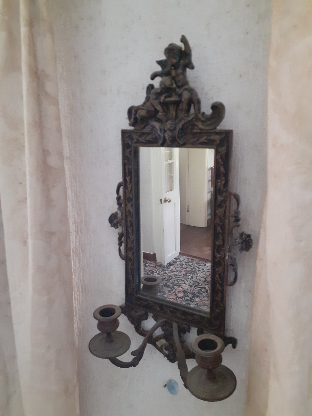 A Victorian cast brass wall mirror with cherub top