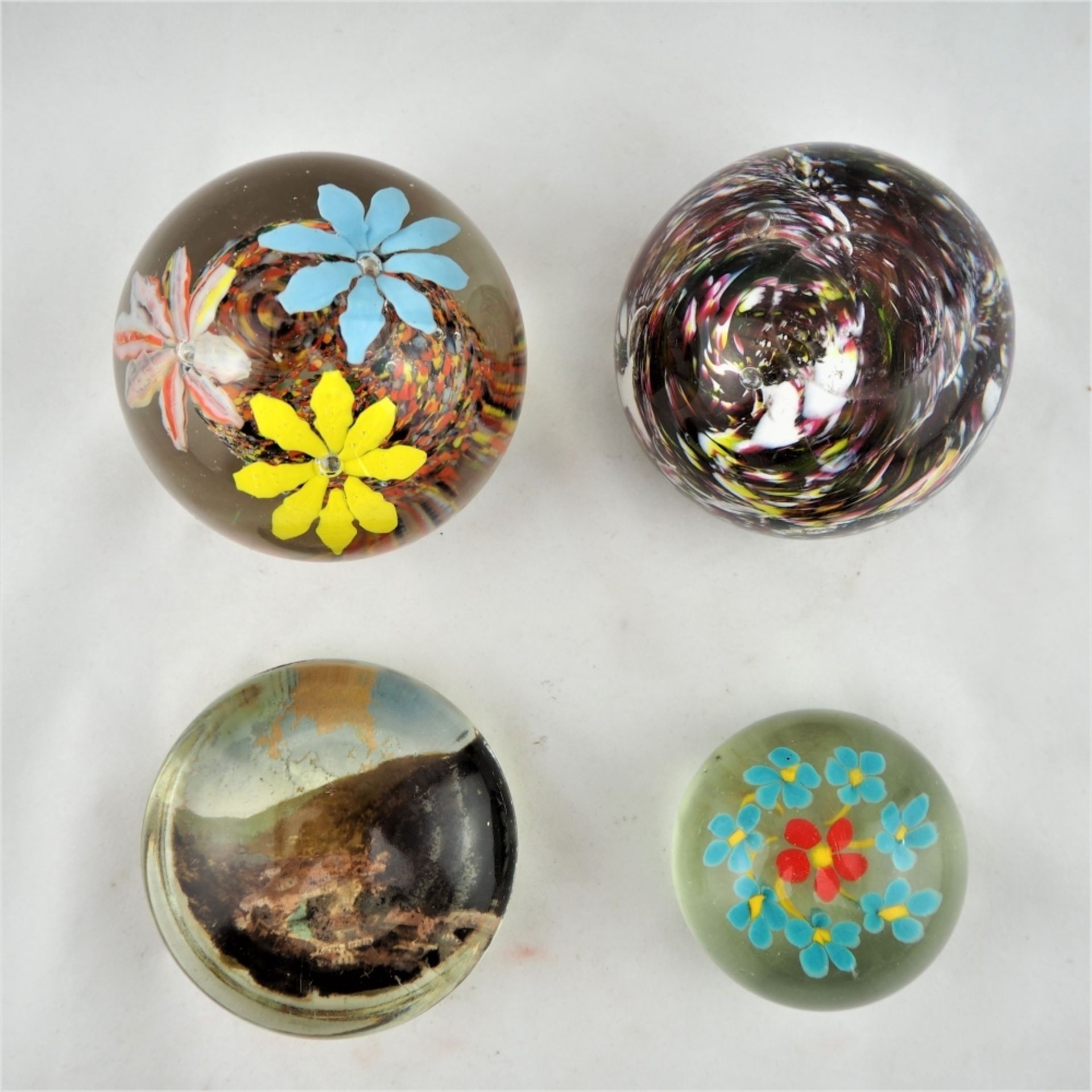 Konvolut Paperweights, 4 StückKugeln aus Klarglas mit Einschmelzungen, teils mit stilisi