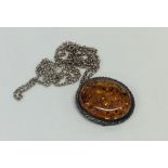 A small silver and amber pendant on fine link chai
