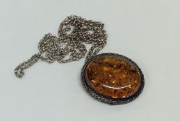 A small silver and amber pendant on fine link chai