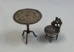A silver filigree tripod table together with a cha