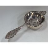 A heavy silver tea strainer on stand with scroll h