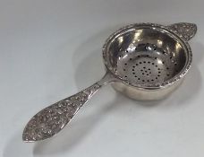 A heavy silver tea strainer on stand with scroll h