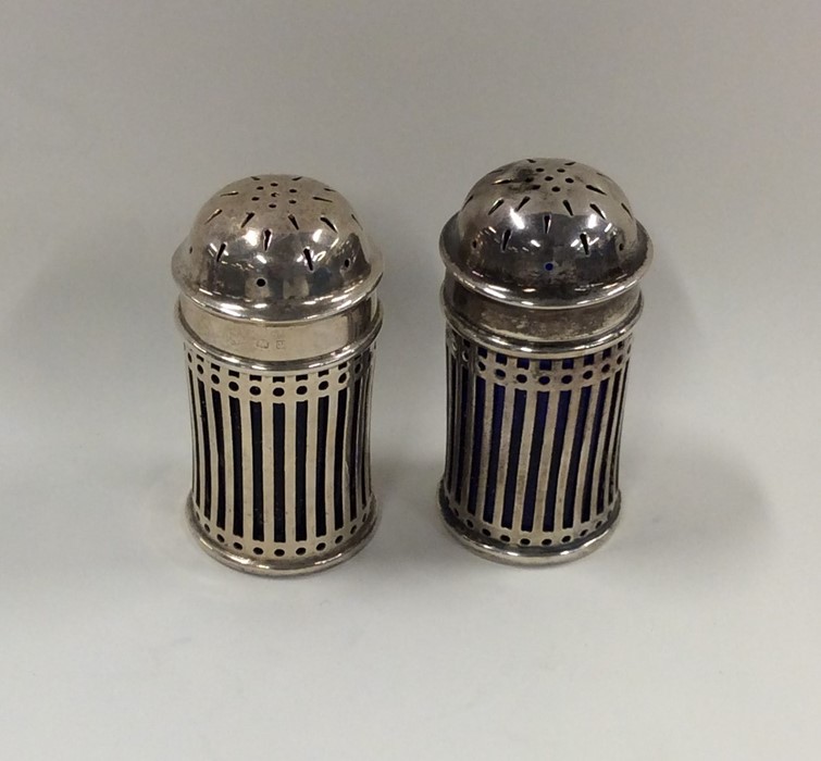 A pair of Edwardian silver pierced peppers with li