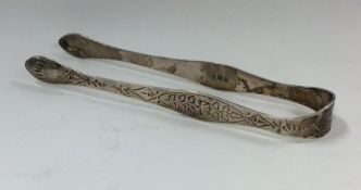 A pair of bright cut silver sugar tongs with flora