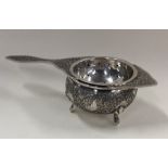 A Persian silver tea strainer on stand with floral
