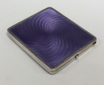 A silver and enamel cigarette case with scroll dec